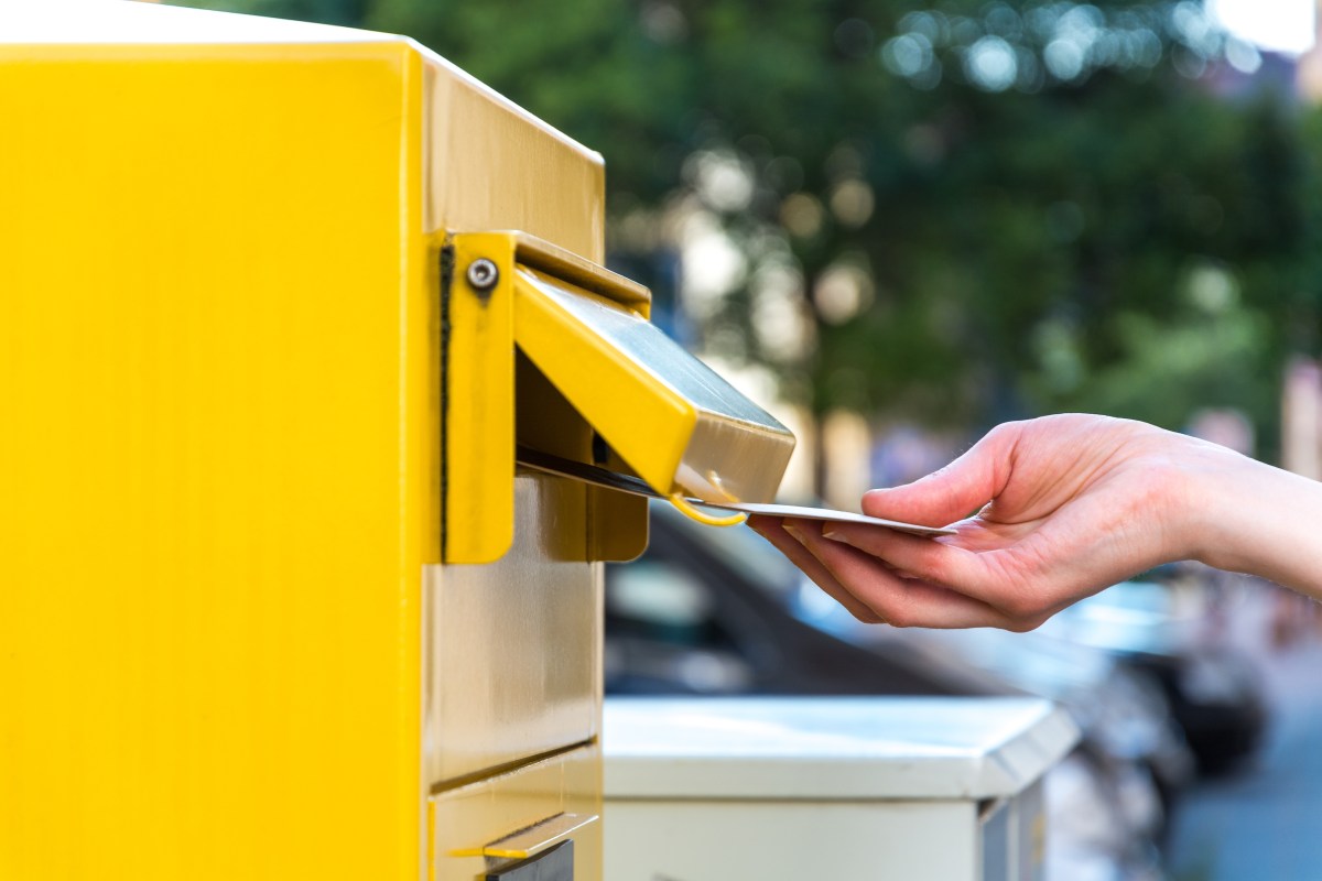 Person schmeißt einen Brief in einen Briefkasten der Deutschen Ost.