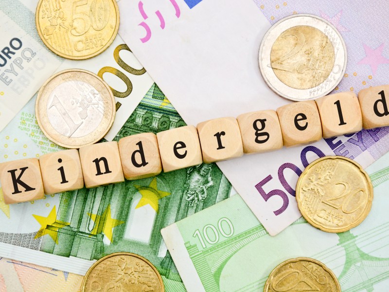 Auf Würfeln steht das Wort "Kindergeld". Darunter liegen Geldscheine.