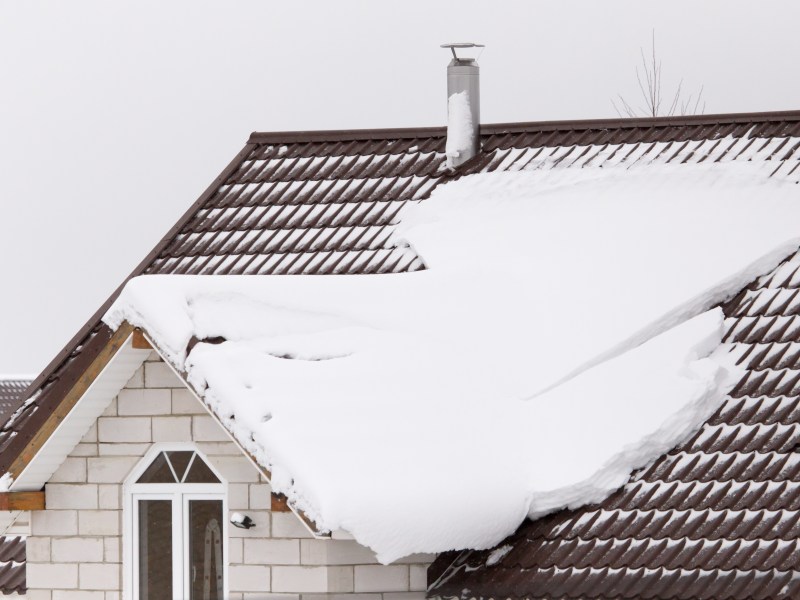 Schnee liegt auf einem Hausdach.