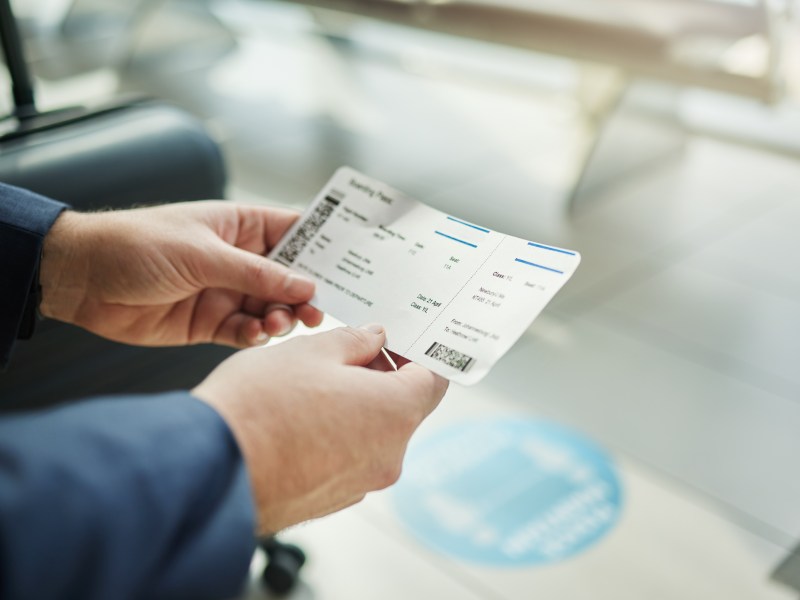 Eine Person hält ein Flugticket in der Hand.