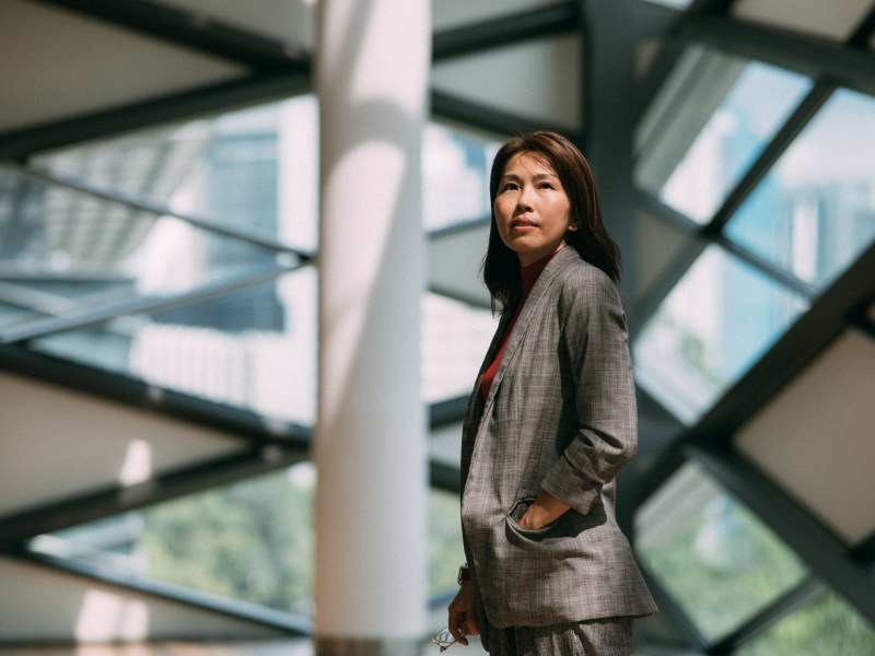 Selbstbewusste asiatisch-chinesische Geschäftsfrau steht am Fenster im Büro.