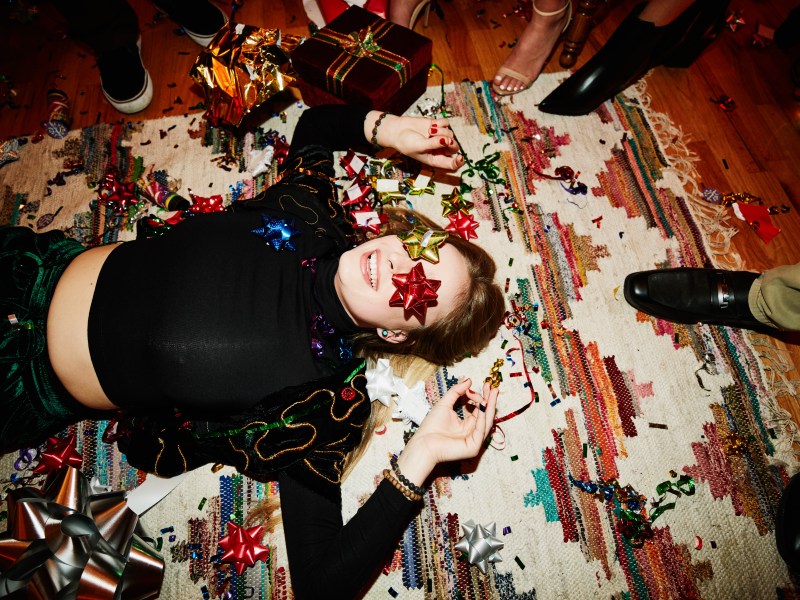 Lachende Frau liegt während einer Weihnachtsfeier auf dem Boden