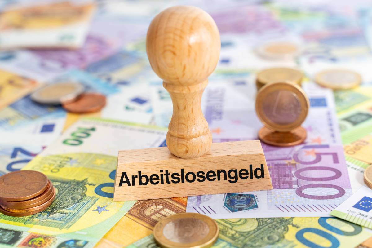 Ein Stempel mit der Aufschrift "Arbeitslosengeld" steht auf Geldscheinen.