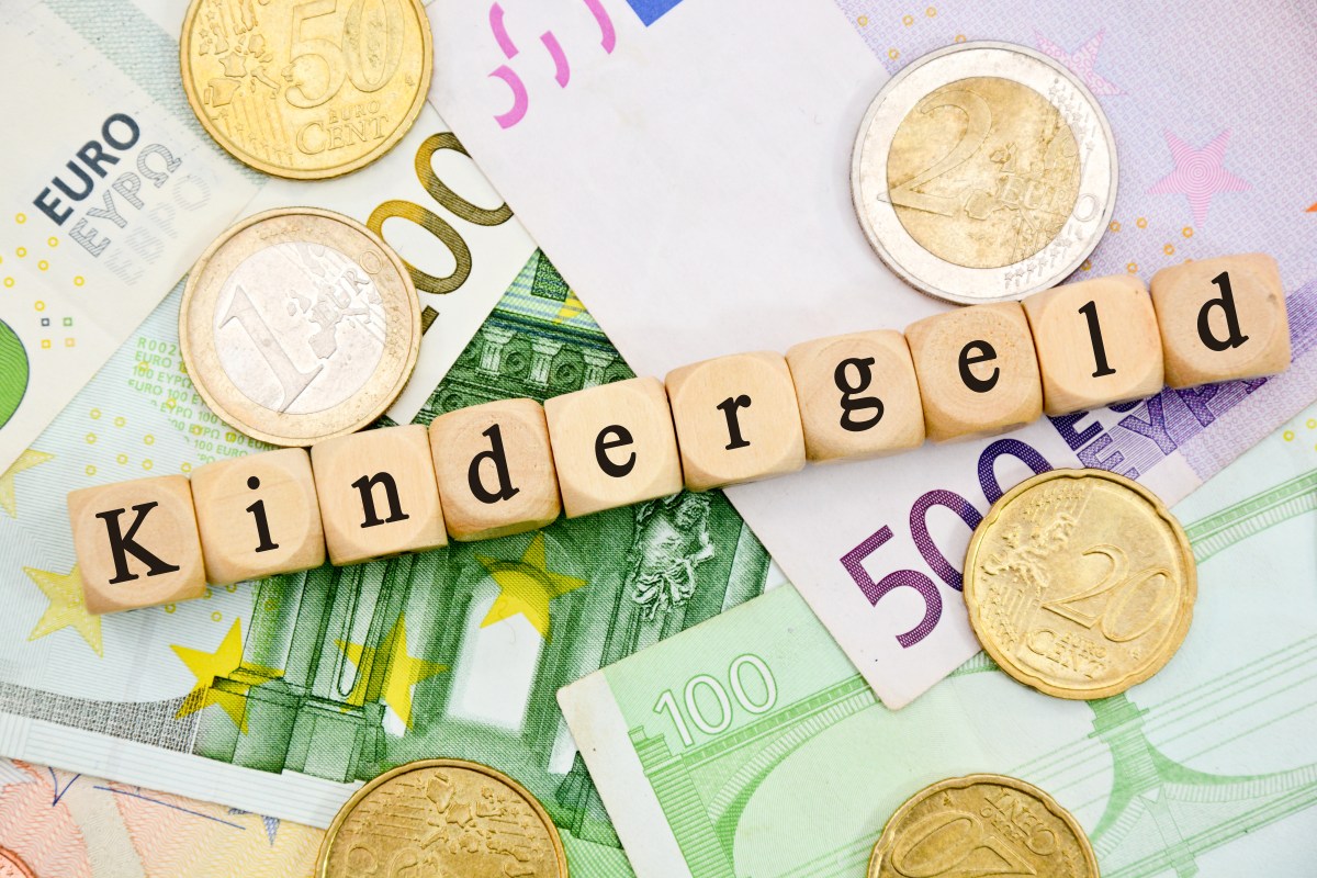 Auf Holzwürfeln steht das Wort "Kindergeld". Darunter liegen Geldscheine.