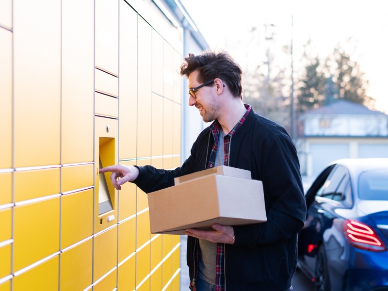 Ein Mann bringt ein Paket zu einer Packstation.