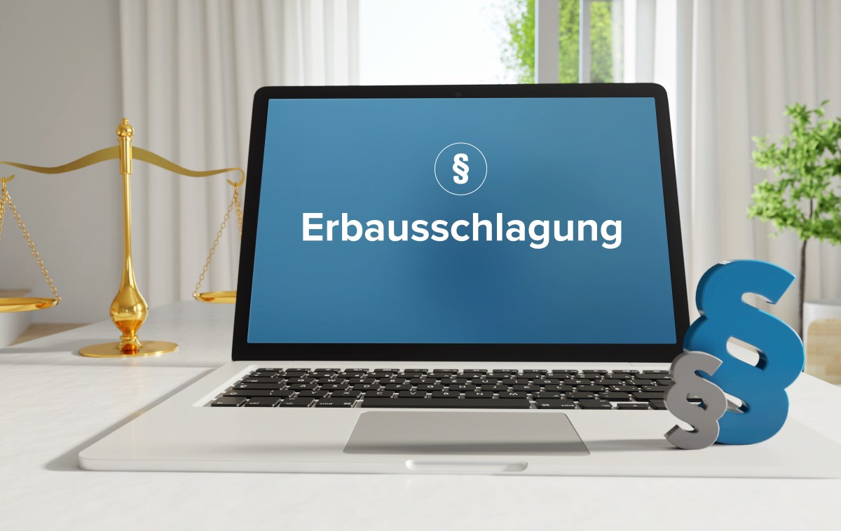 Auf einem Kaptop steht das Wort "Erbausschlagung". Daneben steht eine Gerichtswaage.