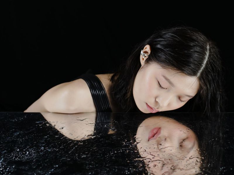 Frau blinkt in einen nassen Spiegel