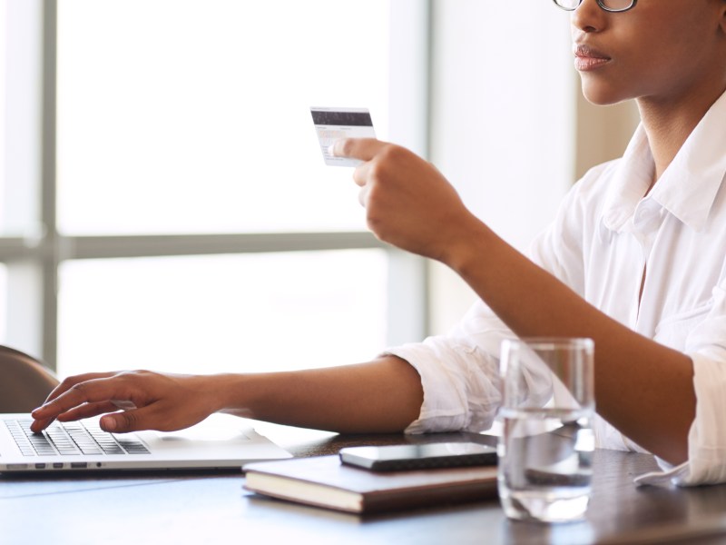 Eine Frau sitzt mit ihrer Bankkarte am Laptop.