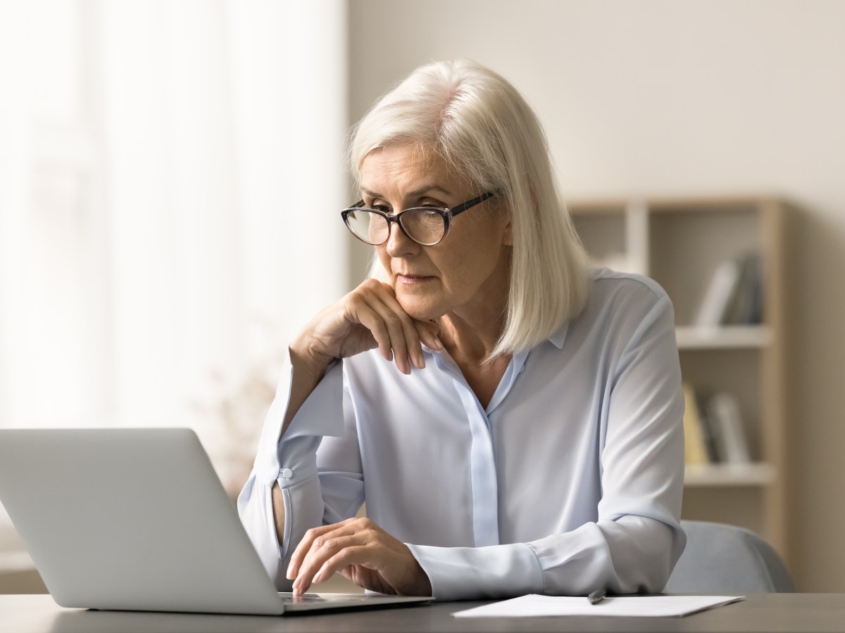 Eine Ã¤ltere Dame sitzt vor dem Laptop und arbeitet.