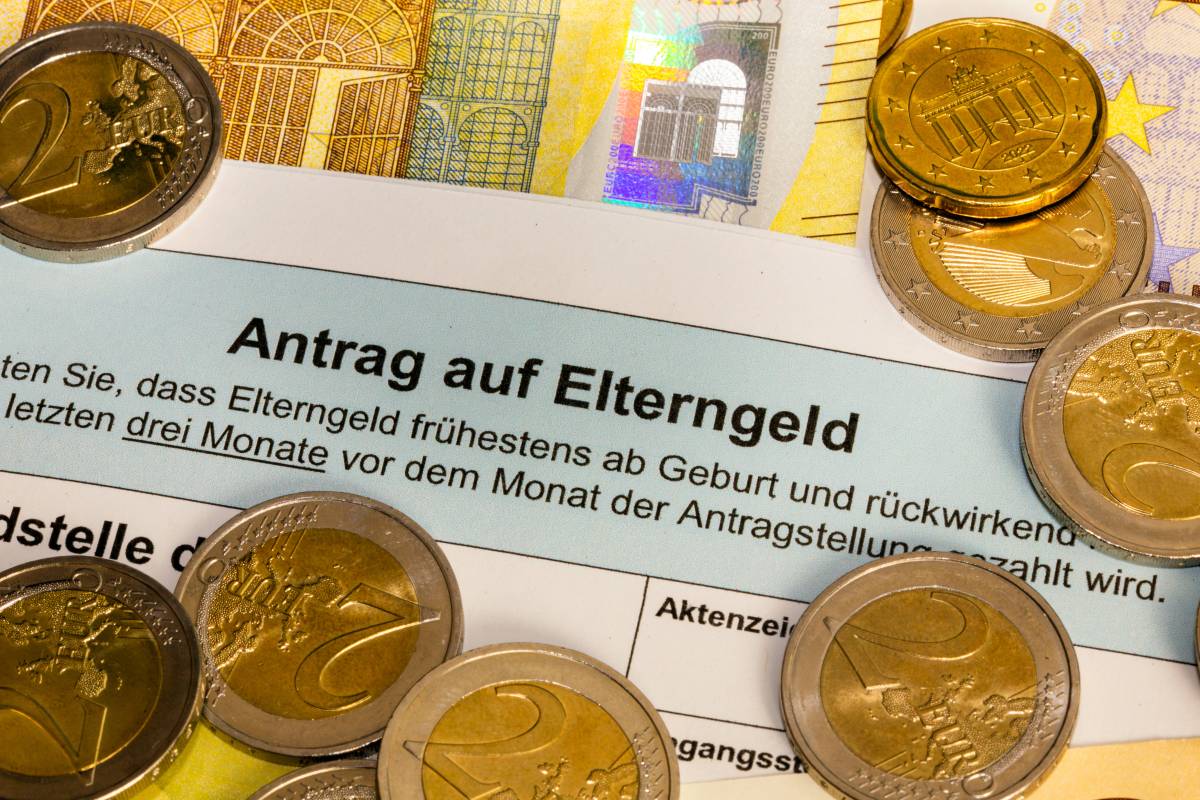 Zwischen MÃ¼nzen und Geldscheinen liegt ein Antrag auf Elterngeld.