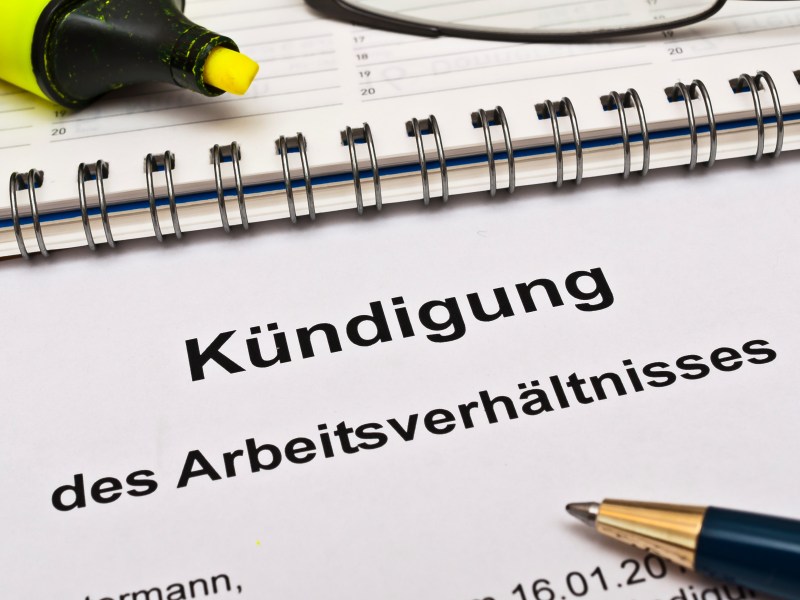 Auf einem Blattpapier steht die Aufschrift "Kündigung des Arbeitsverhältnisses". Daneben liegt ein Kugelschreibe.