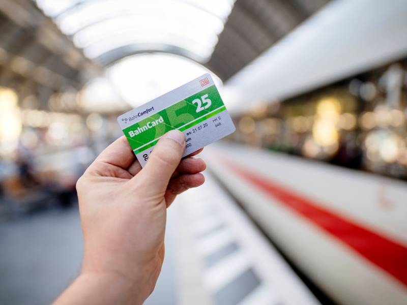 Eine Person hÃ¤lt am Gleis eine BahnCard 25 in der Hand. Im Hintergrund ist ein ICE zu sehen.