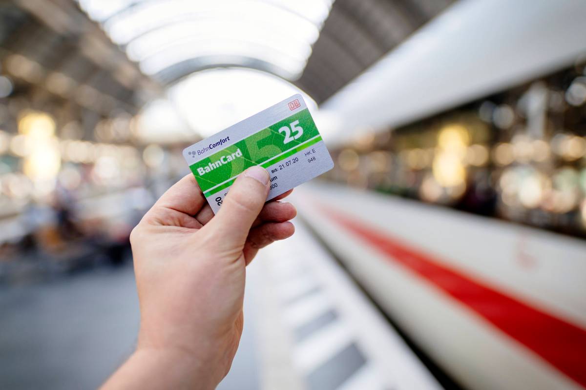 Eine Person hÃ¤lt am Gleis eine BahnCard 25 in der Hand. Im Hintergrund ist ein ICE zu sehen.