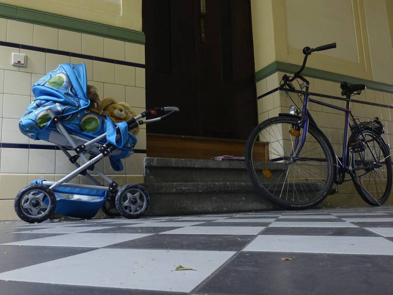 Ein Fahrrad und ein Kinderwagen stehen im Hausflur.