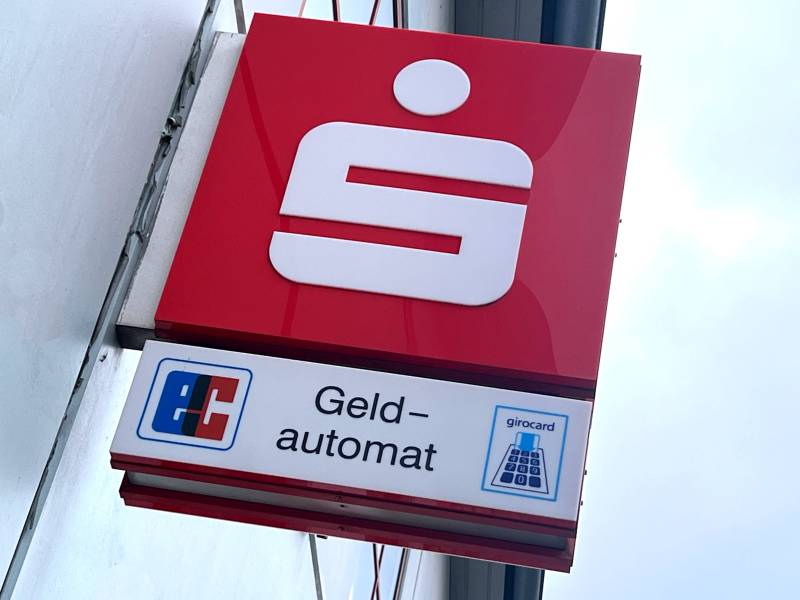 Ein Logo der Sparkasse hängt an einem Gebäude.