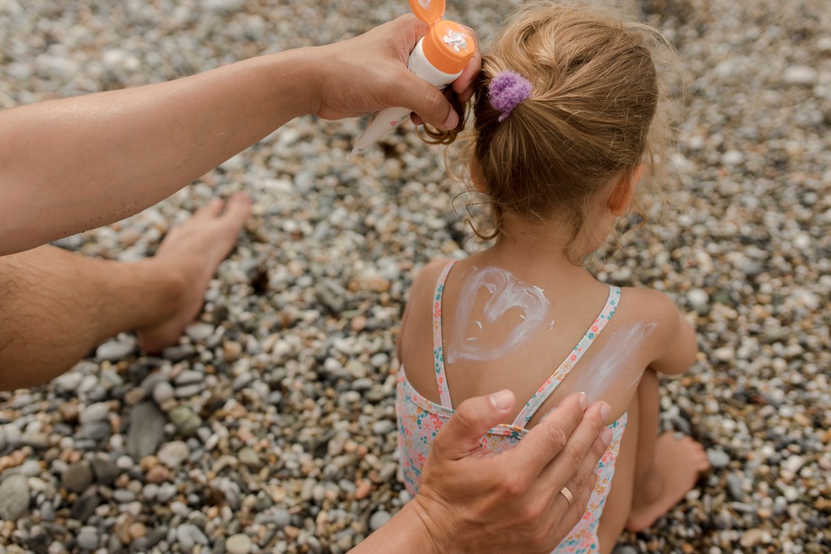 Kind wird mit Sonnencreme eingecremt