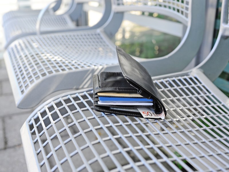 Ein Portemonnaie liegt einsam auf einer Bank.
