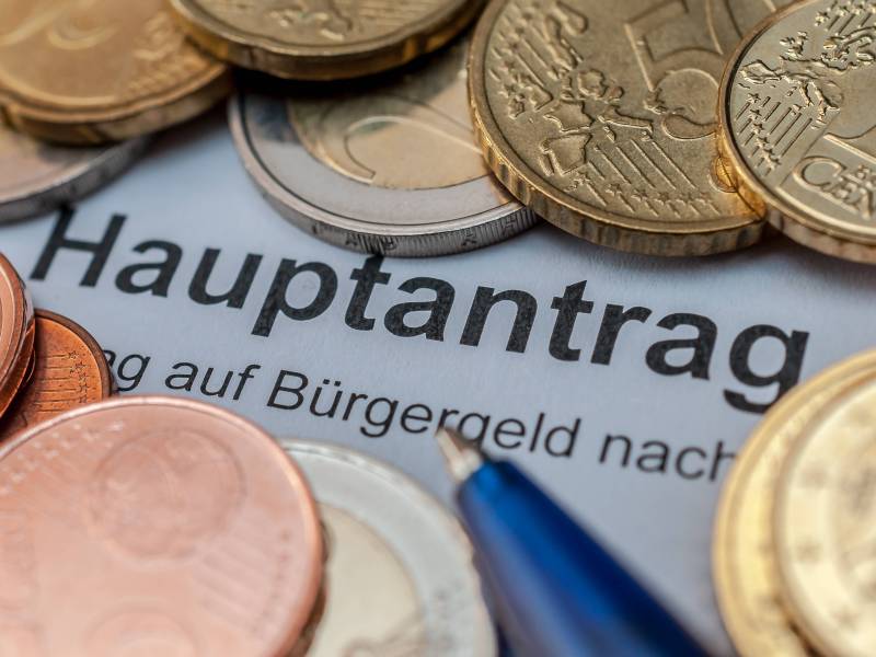 Ein Bürgergeld-Hauptantrag liegt zwischen vielen Euro-Münzen.