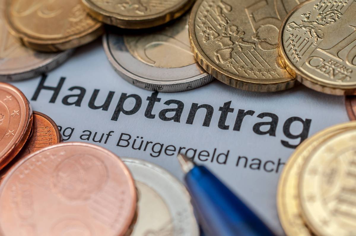 Ein Bürgergeld-Hauptantrag liegt zwischen vielen Euro-Münzen.