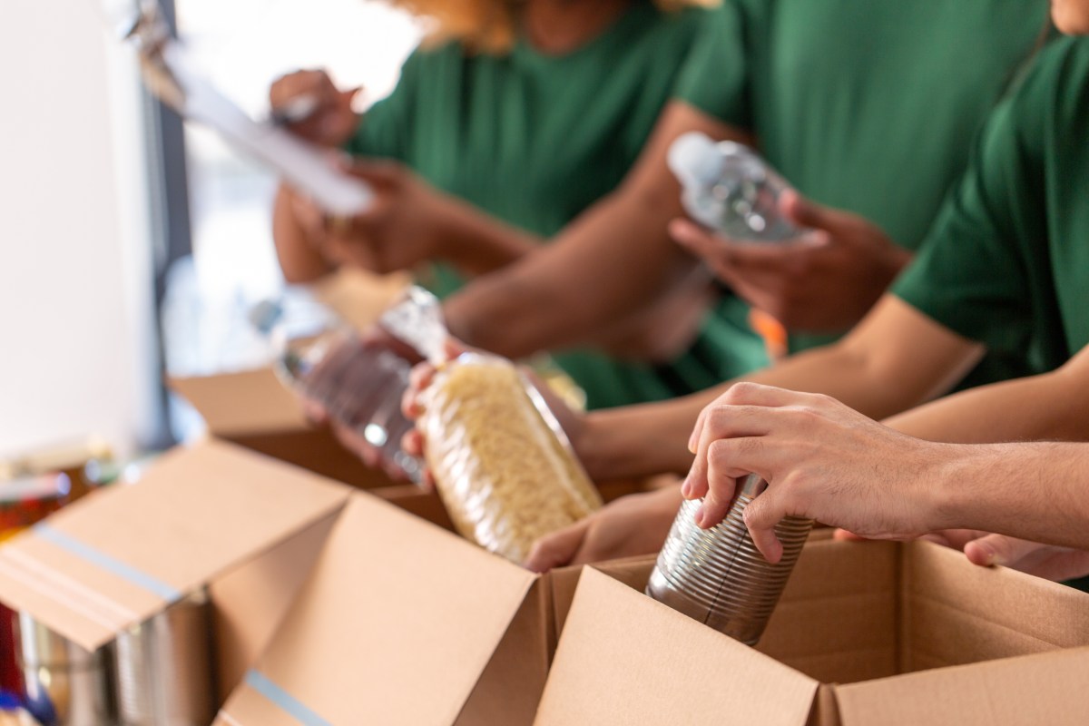 Personen packen Lebensmittel in Kartons.