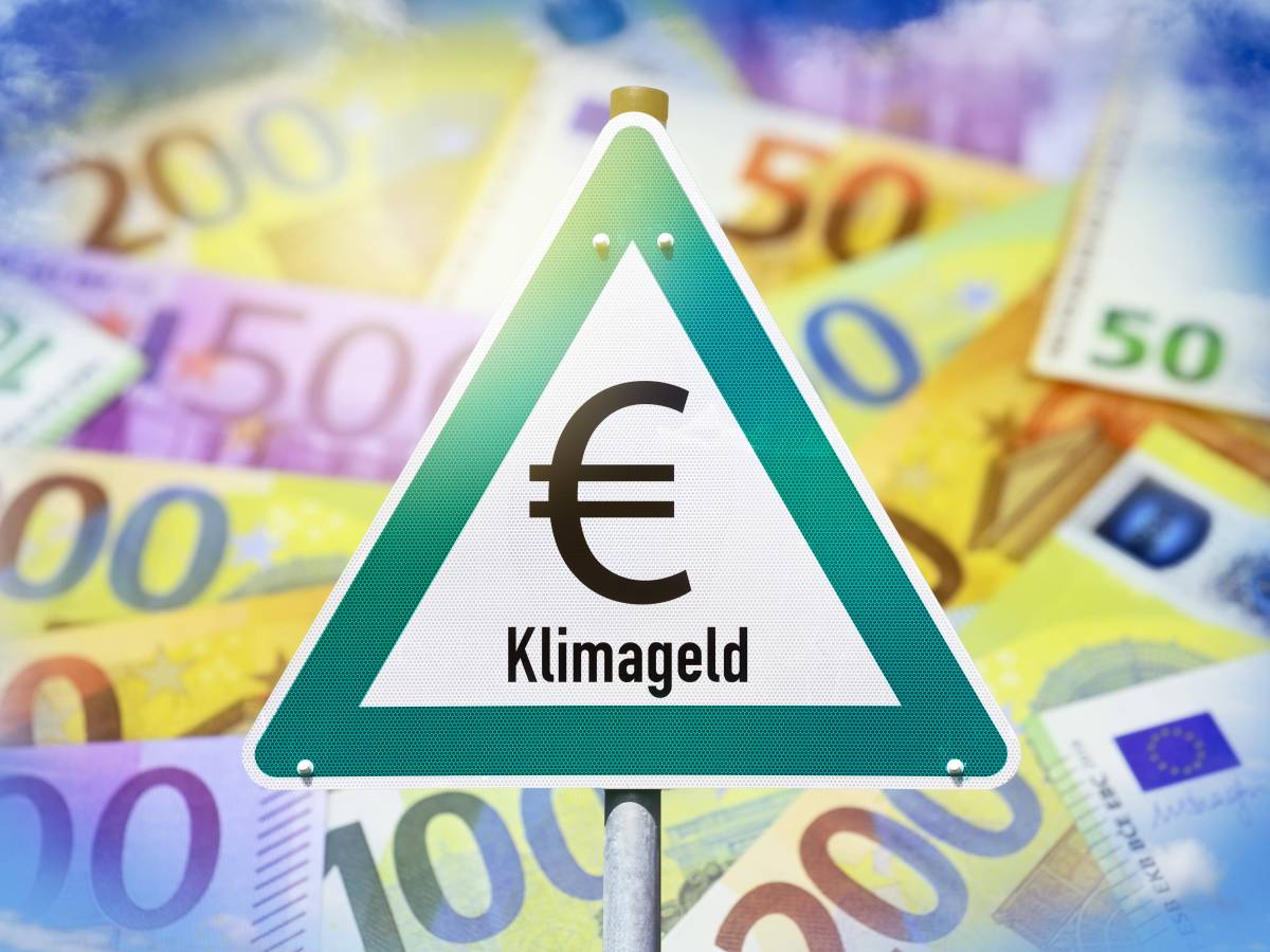 Auf einem Warnschild steht das Wort "Klimageld". Dahinter sind viele Geldscheine.