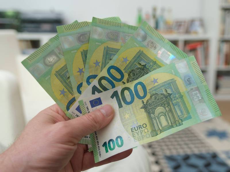 Eine Person hält fünf 100-Euro-Scheine in der Hand.