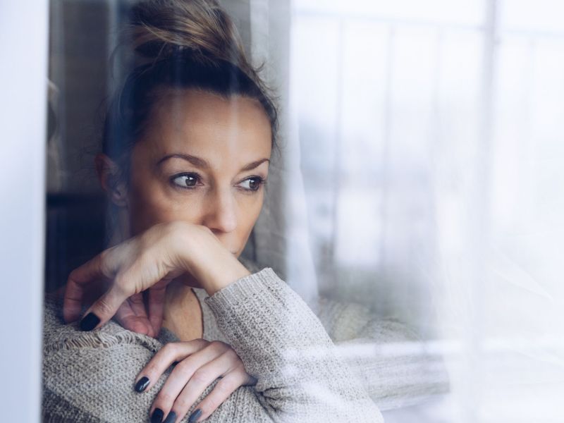 Frau mit Einsamkeit schaut aus dem Fenster