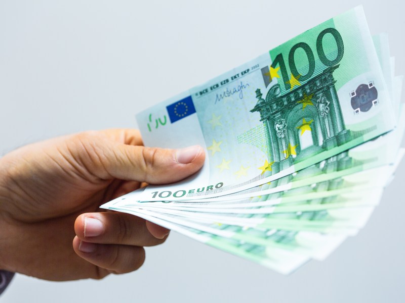 Eine Person hÃ¤lt mehrere 100-Euro-Scheine in der Hand.