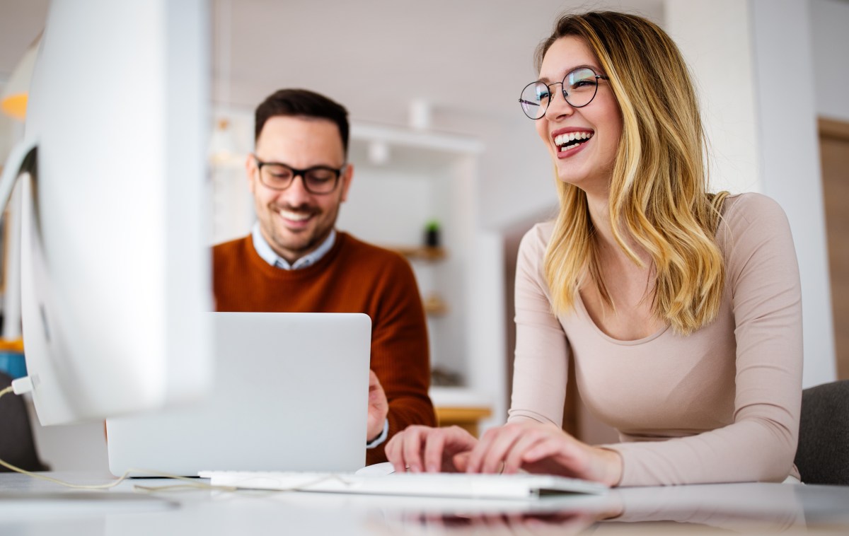 Ein Mann und eine Frau sitzen im Büro am Laptop.