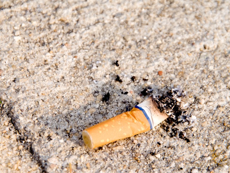 Ein Zigarettenstummel liegt auf dem Asphalt.