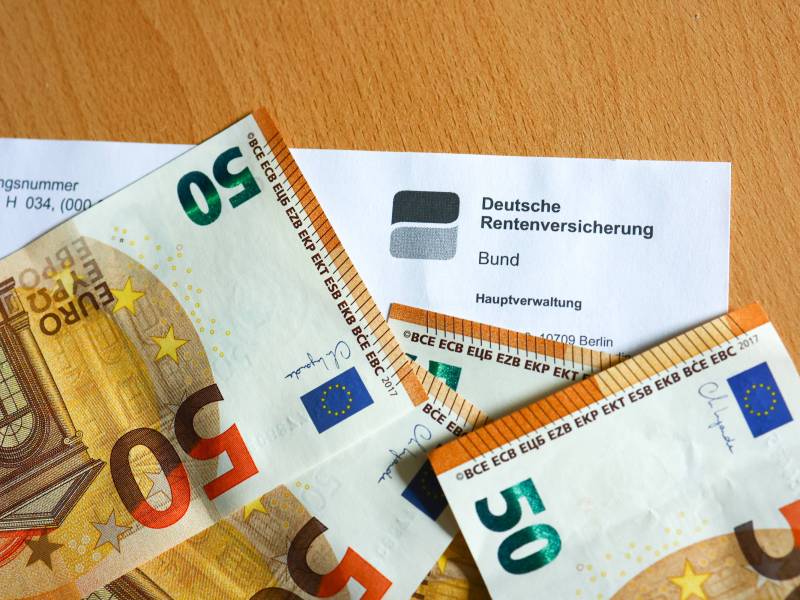 Neben einem Rentenbescheid liegen drei 50-Euro-Scheine.