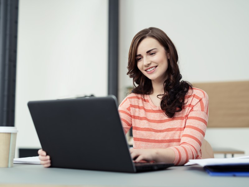 Eine Frau sitzt am Laptop und arbeitet.