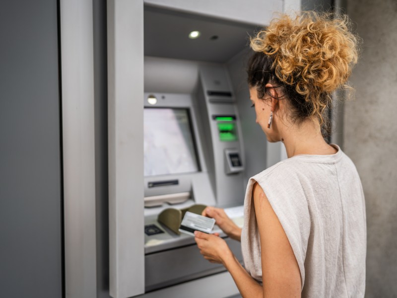 Eine Frau hebt an einem Bankautomaten Geld ab.