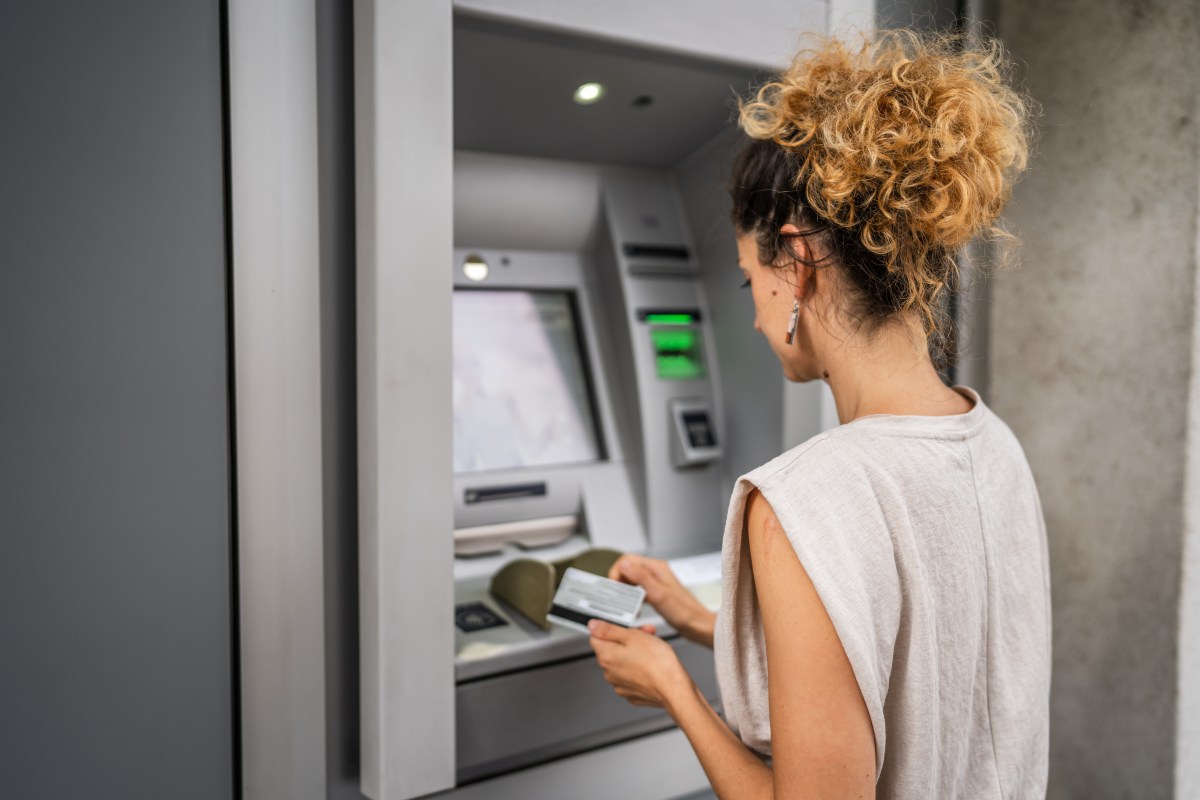 Eine Frau hebt an einem Bankautomaten Geld ab.