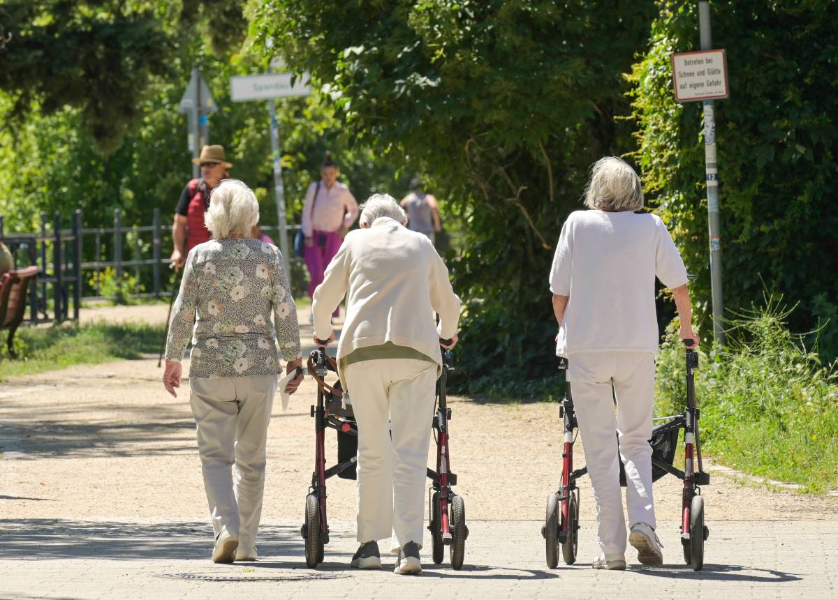 Eine Gruppe von Seniorinnen. Zwei gehen am Rollator.