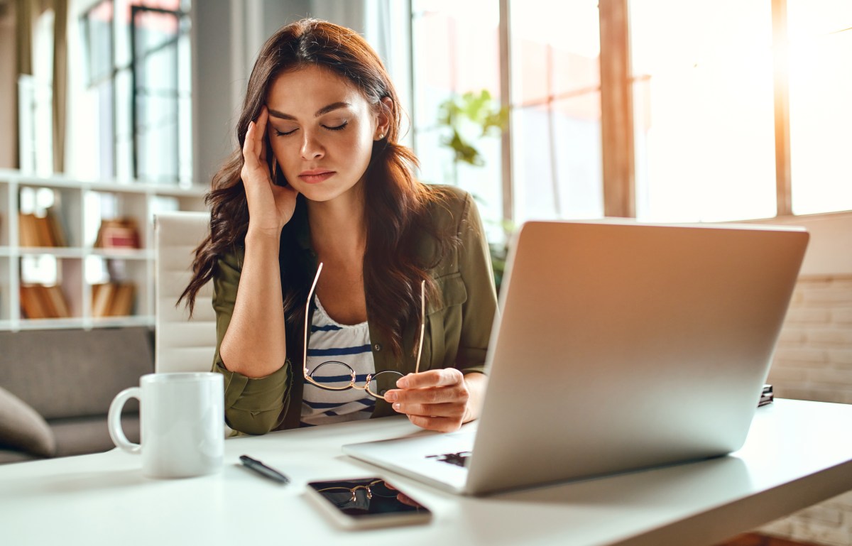 Eine Frau sitzt erschöpft im Büro an ihrem Computer.