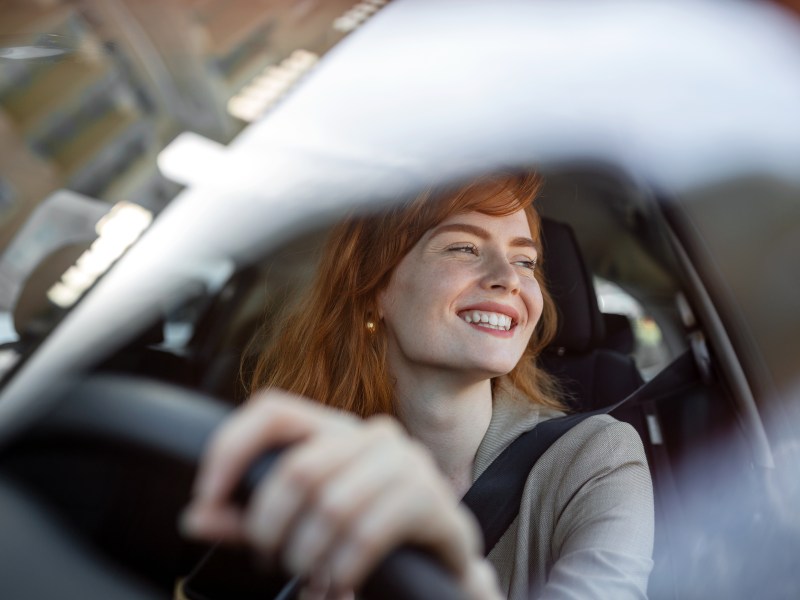 Frau sitzt im Auto und lacht