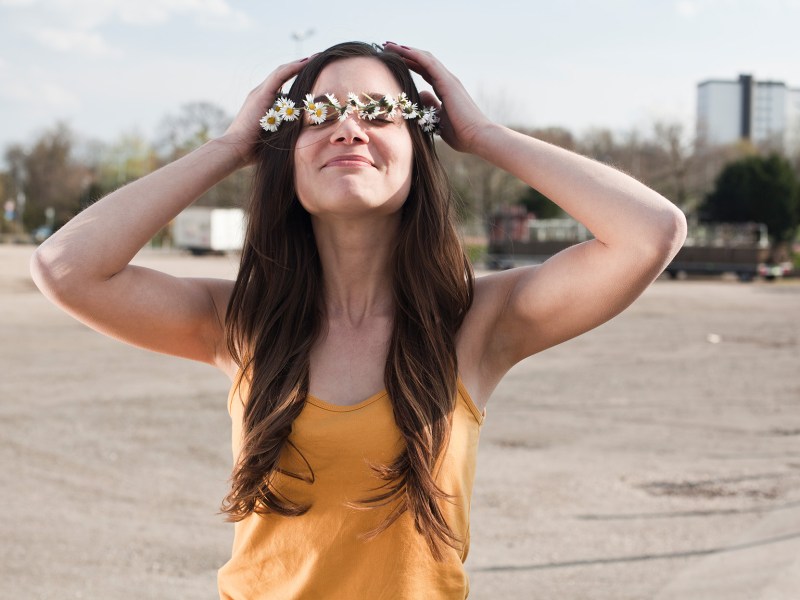 Frau in gelbem Oberteil mit Blumenkranz auf dem Kopf