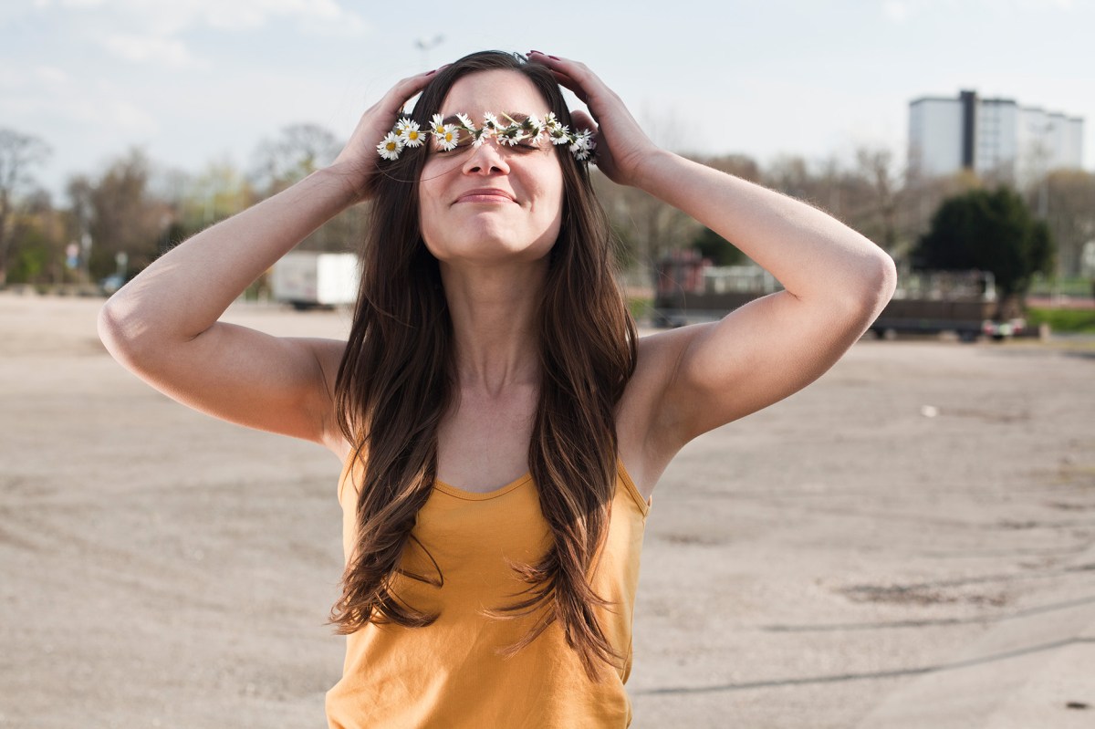 Frau in gelbem Oberteil mit Blumenkranz auf dem Kopf