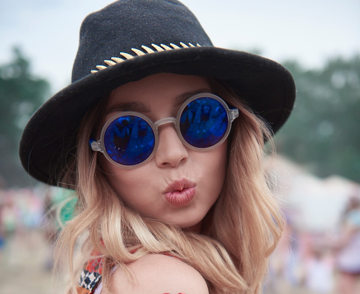 Frau mit Hut auf einem Festival macht Duckface