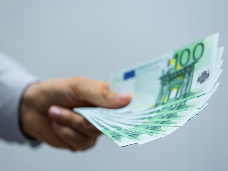 Ein Mann hÃ¤lt mehrere 100-Euro-Scheine in der Hand.