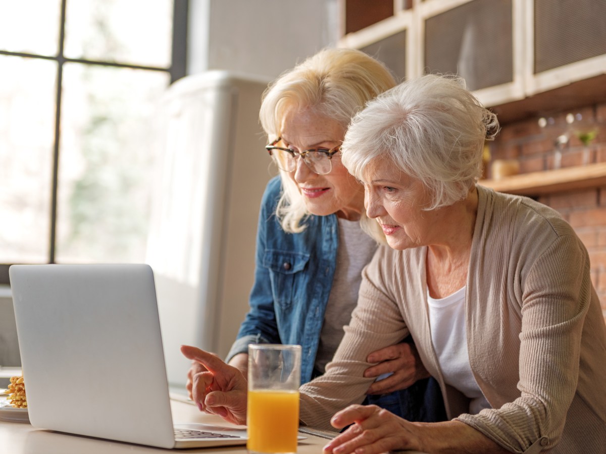 Zwei Seniorinnen schauen auf einen Laptop.