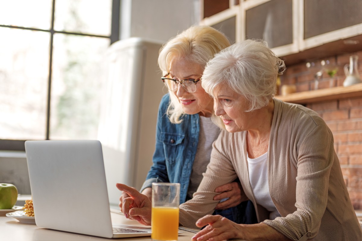 Zwei Seniorinnen schauen auf einen Laptop.