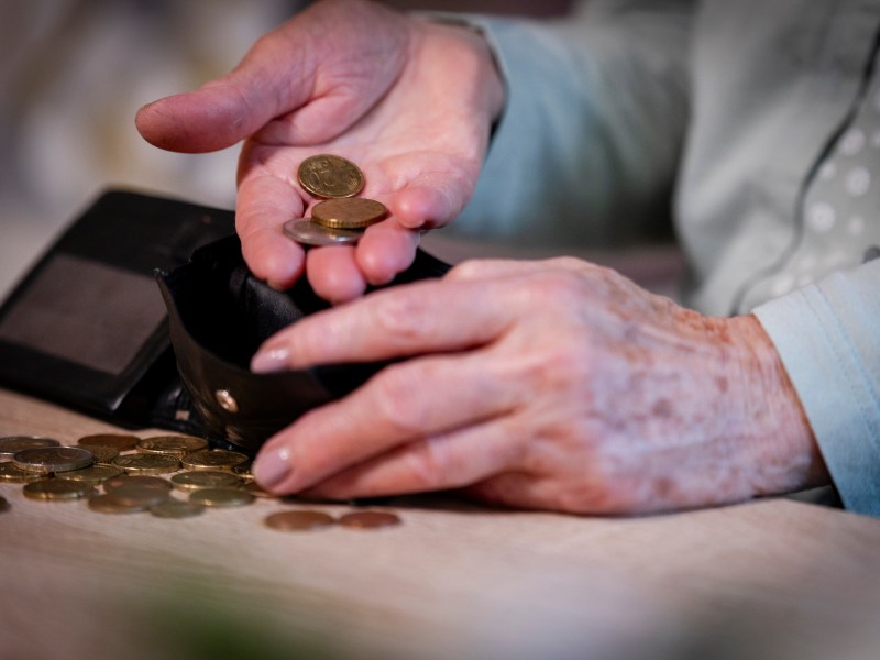 Ältere Person holt Münzen aus dem Portemonnaie.