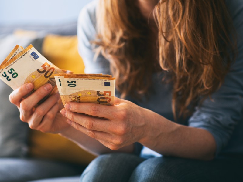 Eine Frau hält mehrere 50-Euro-Scheine in der Hand.