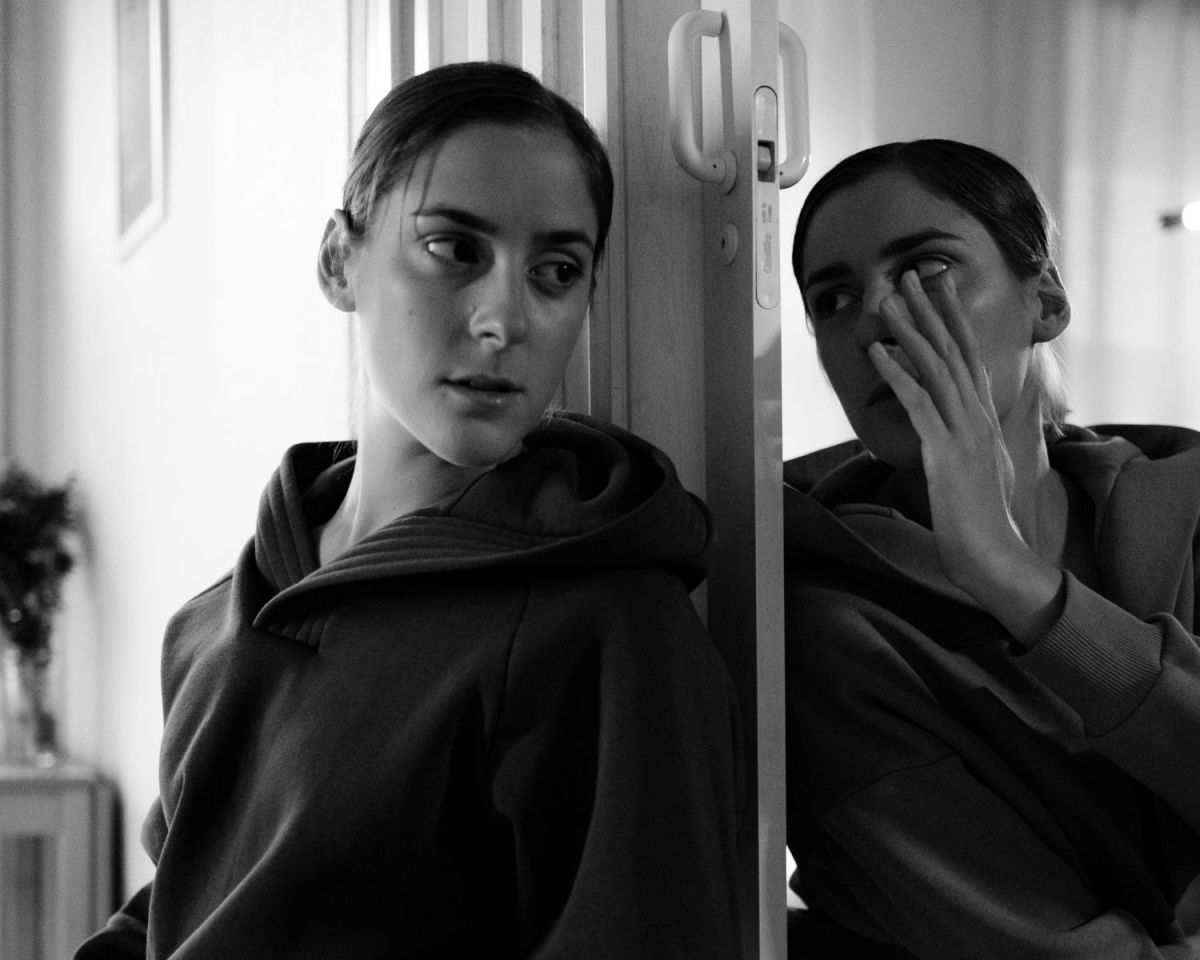 Frau im Spiegelbild flüstert der anderen Frau etwas zu.