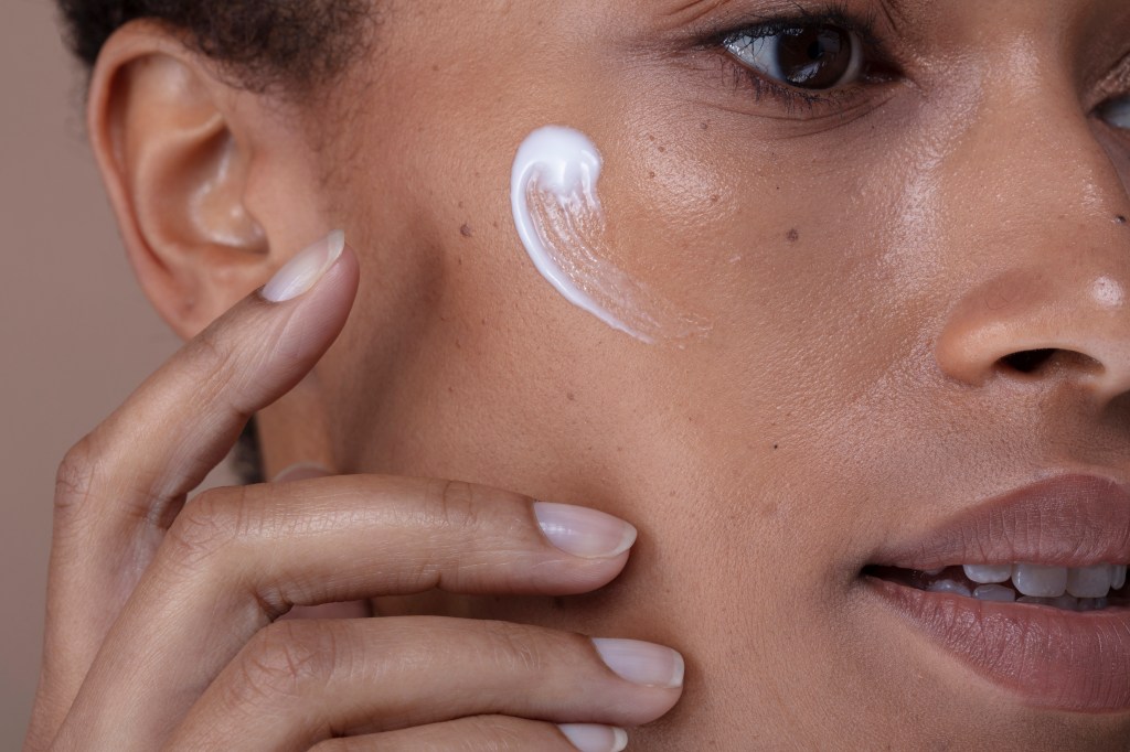 Frau tr&auml;gt Creme auf