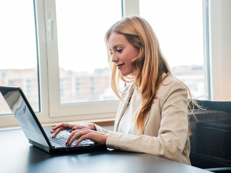Geschäftsfrau arbeitet mit Laptop am Schreibtisch.