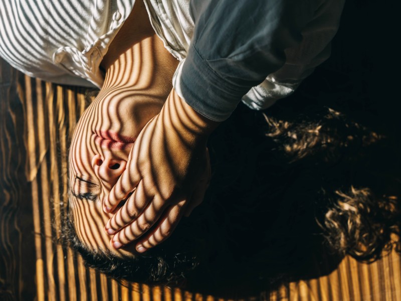 Eine Frau ist erschöpft und hält sich ihre Hand vors Auge.