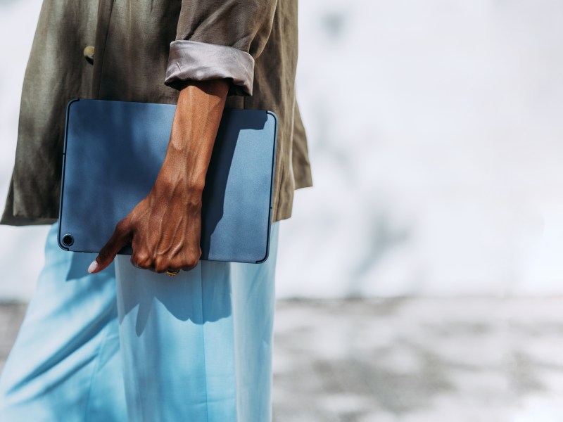 Nahaufnahme eine Geschäftsfrau, die beim Gehen im Freien ein Tablet in der Hand hält.